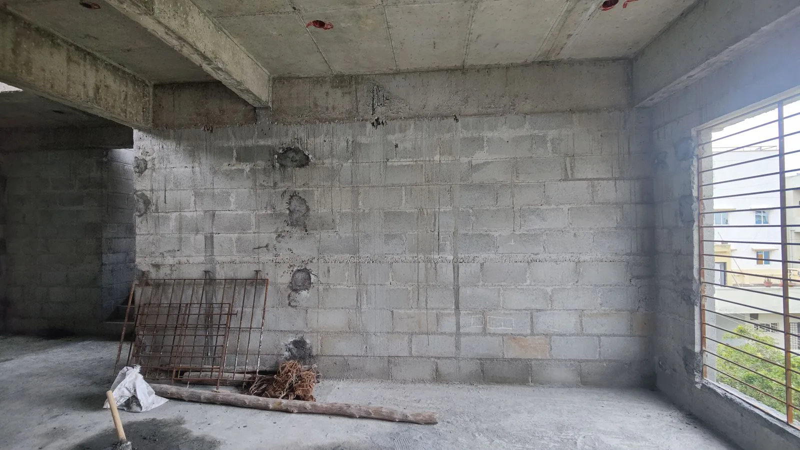 The same living room as a bare shell: block walls, a concrete slab and an unglazed opening.