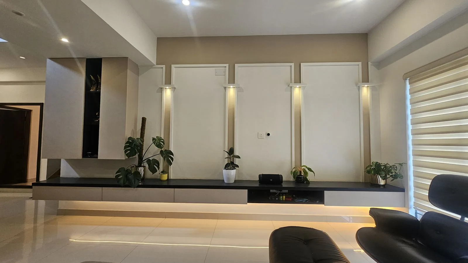 The same living room finished: a lit niche wall, a low console and a fitted sofa.