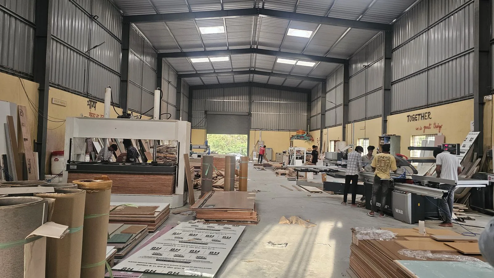 The Haus Projekt factory floor: panel stacks, machines and the long central aisle.